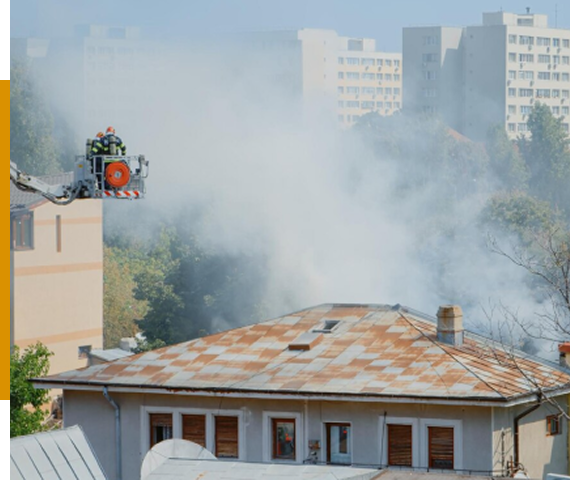 Firefighters on a lift battle heavy smoke from a building fire in a residential area.