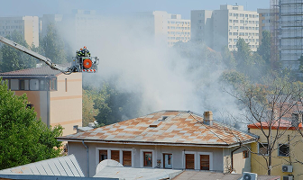 Firefighters on a crane battling a smoky building fire.