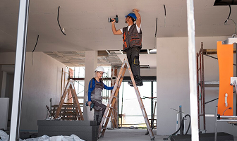 Construction workers installing ceiling wiring.